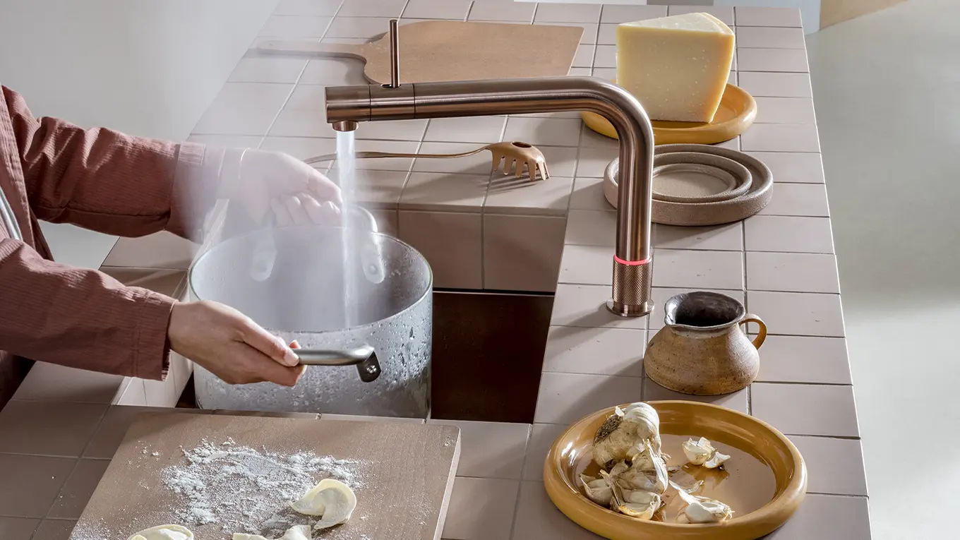 Kochendes wasser wird in einen großen Glastopf aus dem quooker gefüllt