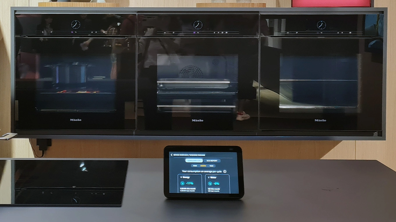 Miele Smart home Tablet auf einer kochinsel vor einer dreier reihe miele backöfen