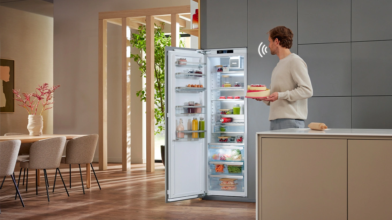 miele activedoor kühlschrank ein mann mit kuchen in der hand öffnet den miele activedoor kühlschrank mit sprachöffnung