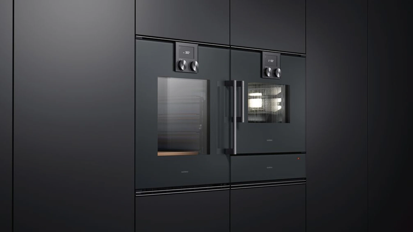 Zwei Dunkle Gaggenau Backöfen aus der Serie 200 in einer schwarzen Küche