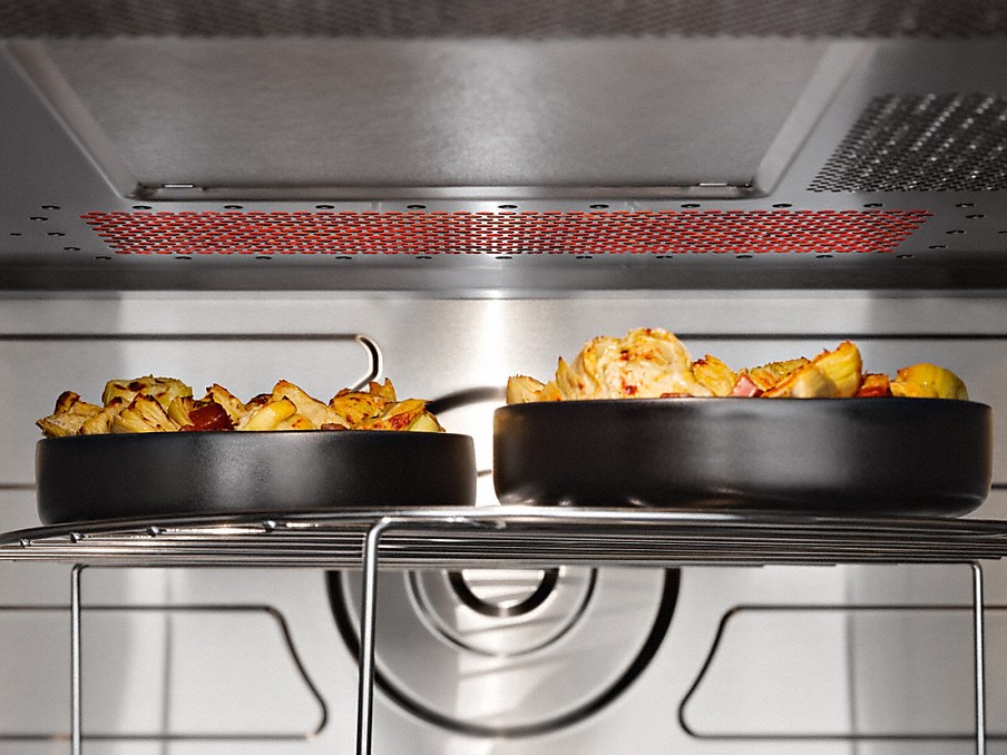 Miele Quarzgrill innenraum einer miele mikrowelle mit quarzgrill beim garen von lebensmitteln in zwei schwarzen tellern