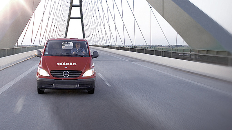 Miele Service Fahrendes rotes Miele Auto auf einer Brücke als Symbolbild für besten Kundenservice