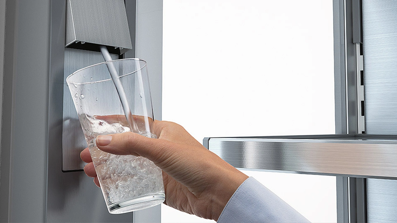 Liebherr Wasserspender am Kühlschrank der ein Glas mit Wasser füllt