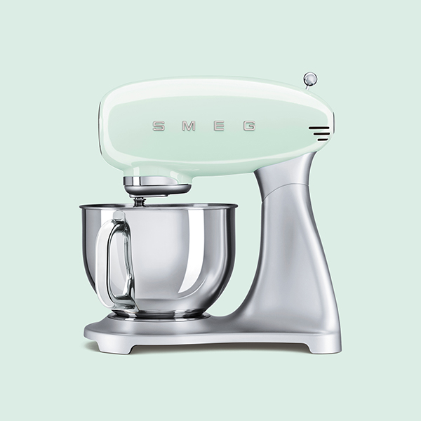 pastellgrüne smeg retro küchenmaschine von der seite vor einem pastell grünen hintergrund