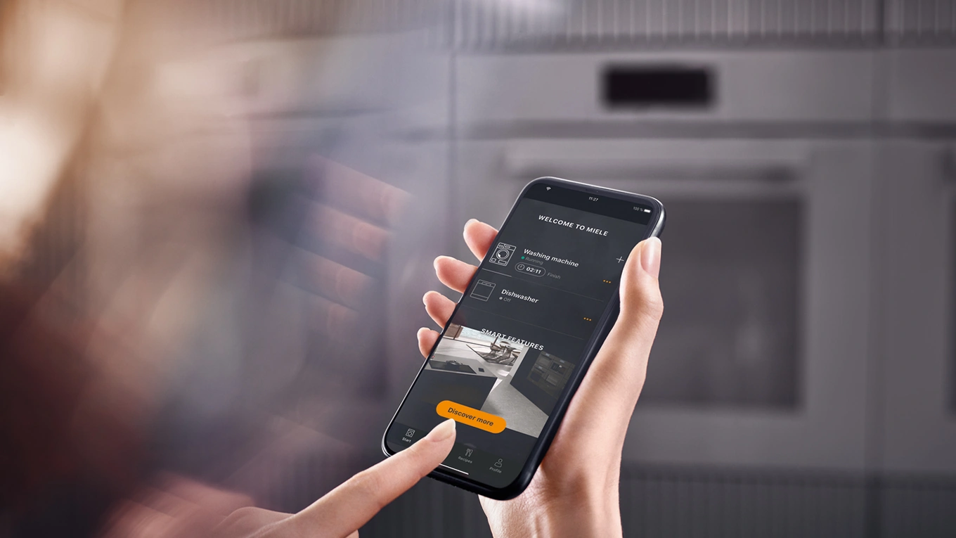 miele app für smarte küchengeräte miele app für smarte küchengeräte auf einem smartphone dispay vor einem unscharfen miele backofen