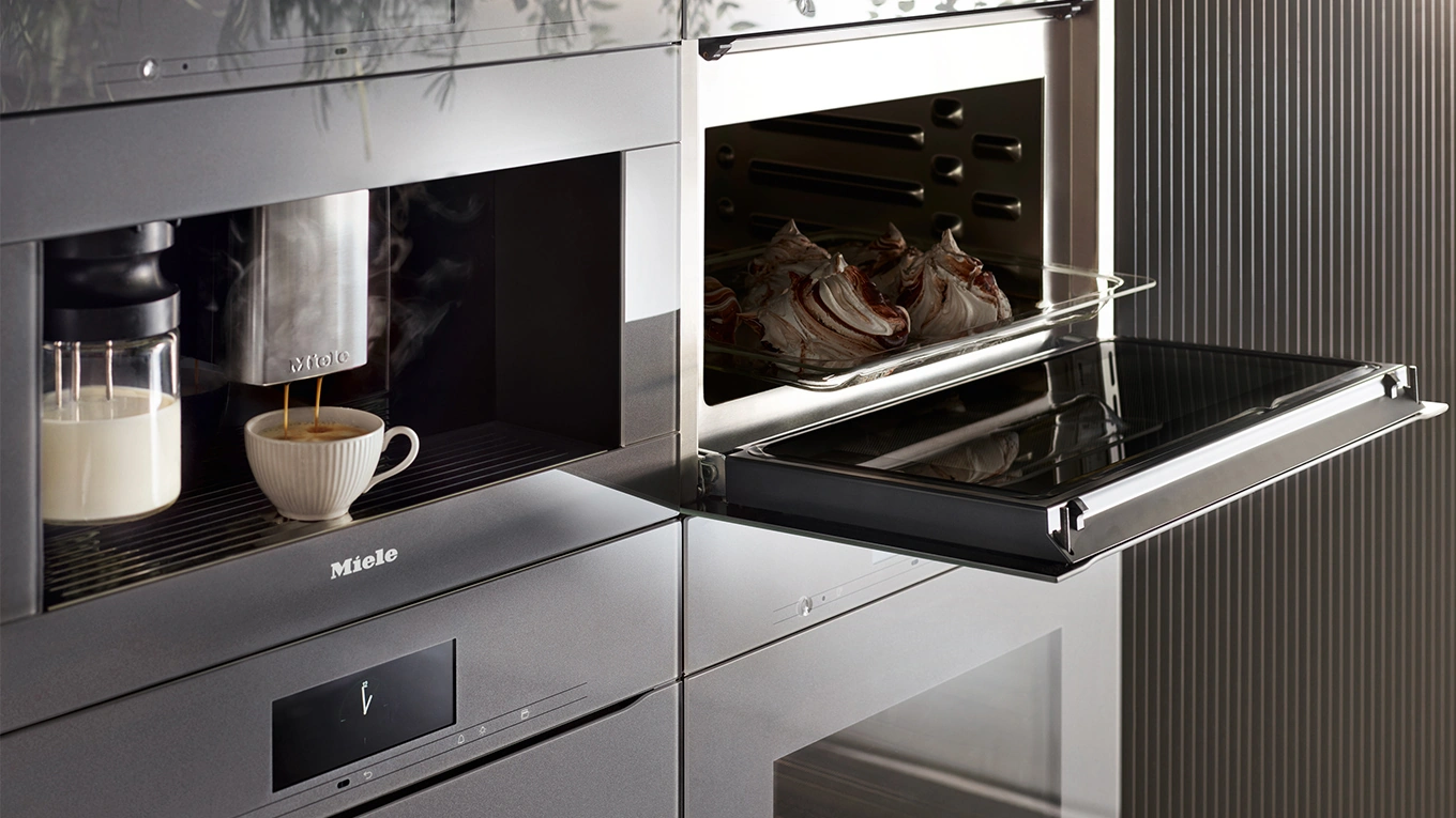 miele einbau kaffeevollautomat mit tasse neben einem backofen in grau