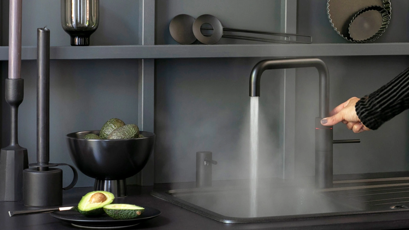 Quooker Wasserhahn quooker wasserhahn eckig in schwarz in einer dunklen küche aus dem heißes wasser läuft