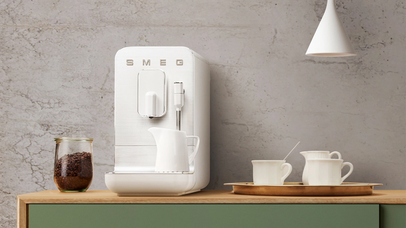 SMEG Mini Kaffeevollautomat weiß smeg mini kaffeevollautomat in weiß mit Kaffeeservice auf einer arbeitsplatte