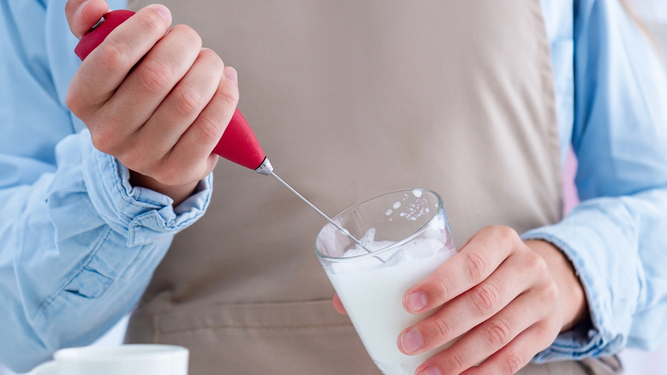 milchaufschäumer stab mann schlägt milch schaumig mit einem roten milchaufschäumer stab