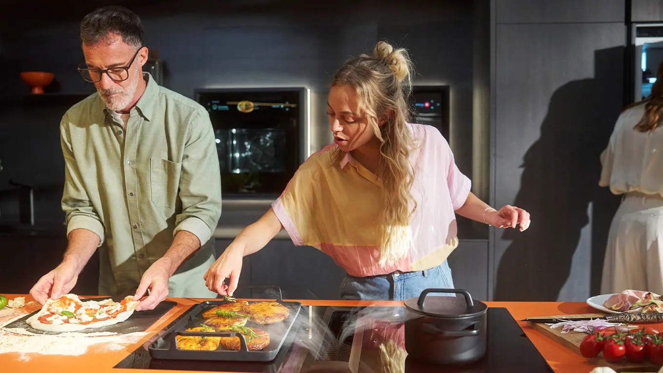 drei personen kochen in einer küche mit bora kochfeld professional