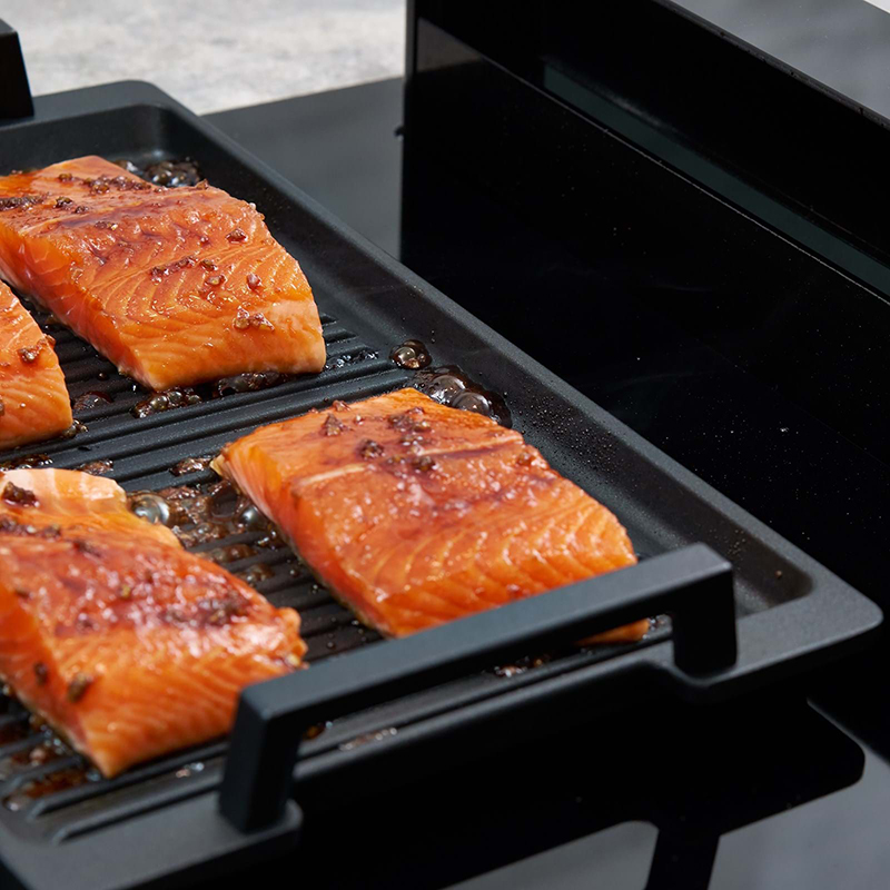 lachsfilets beim braten auf einem grillrost auf einem novy kochfeld