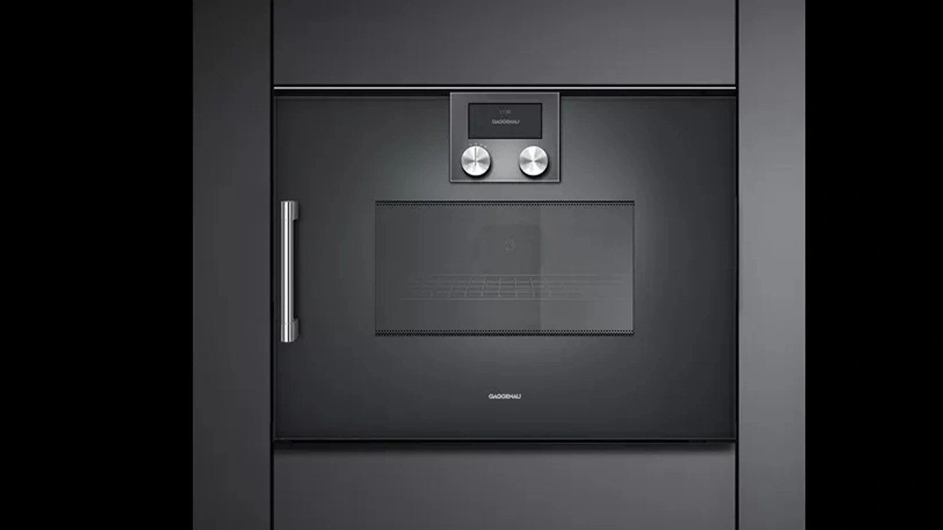 Gaggenau Serie 200 Mikrowellen Backofen Schwarzer Mikrowellen-Backofen aus der Gaggenau Serie 200 mit Griff in einer dunklen Küchenfront eingebaut