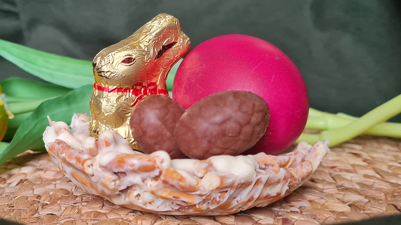 osterhase und drei ostereier im salzstangen osternest