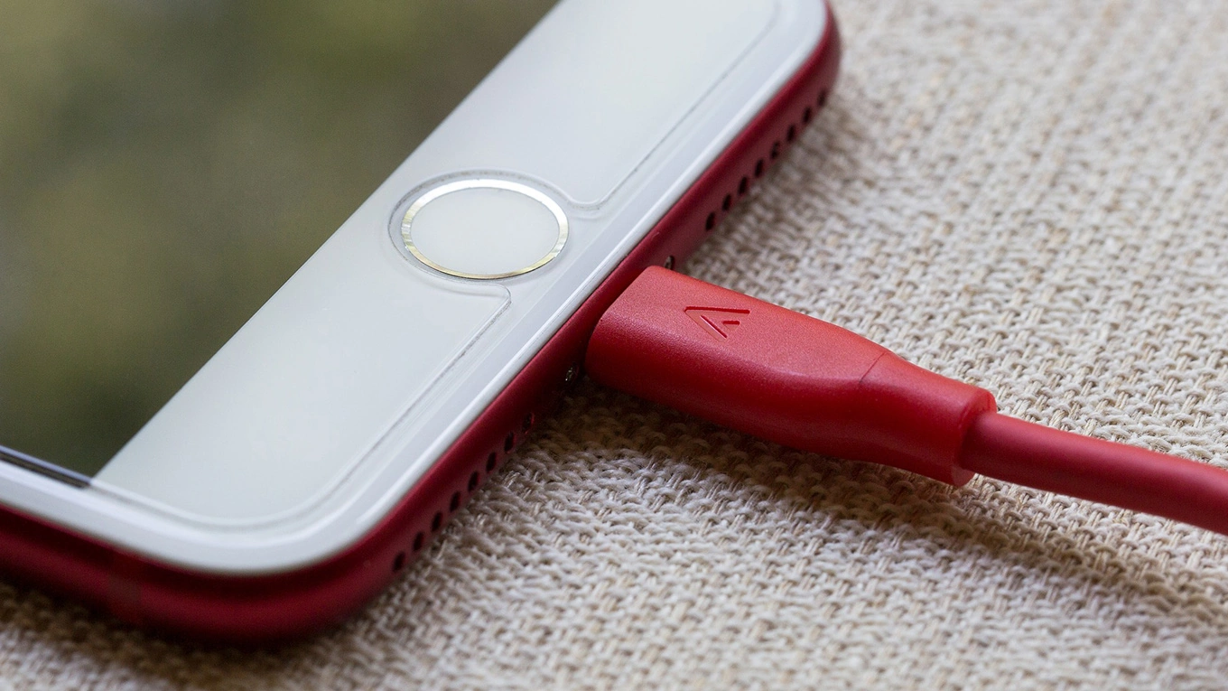 Smartphone aufladen detailaufnahme von einem smartphone das über ein rotes kabel aufgeladen wird
