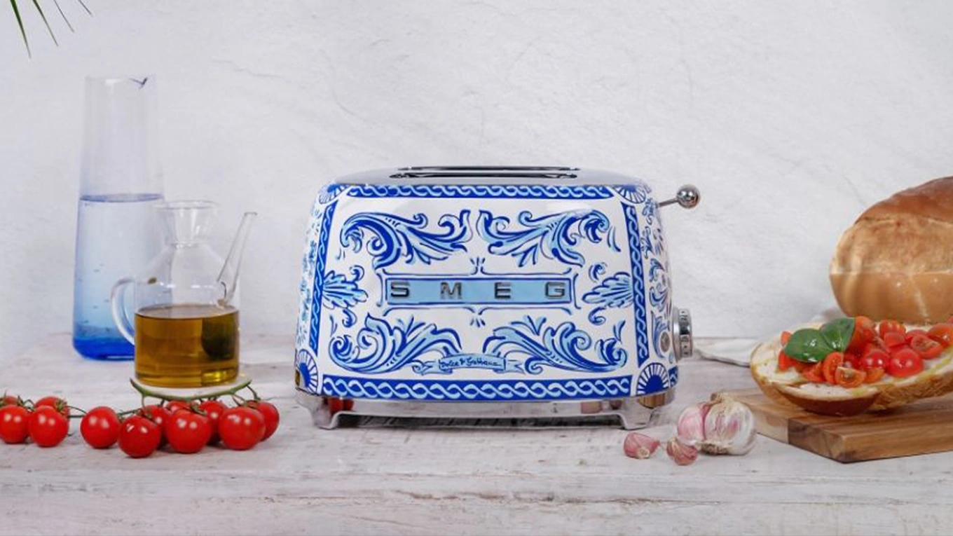 smeg dolce & gabbana blue mediterraneo 2-schlitz-toaster smeg dolce & gabbana blue mediterraneo toaster in blau-weiß neben tomaten und öl