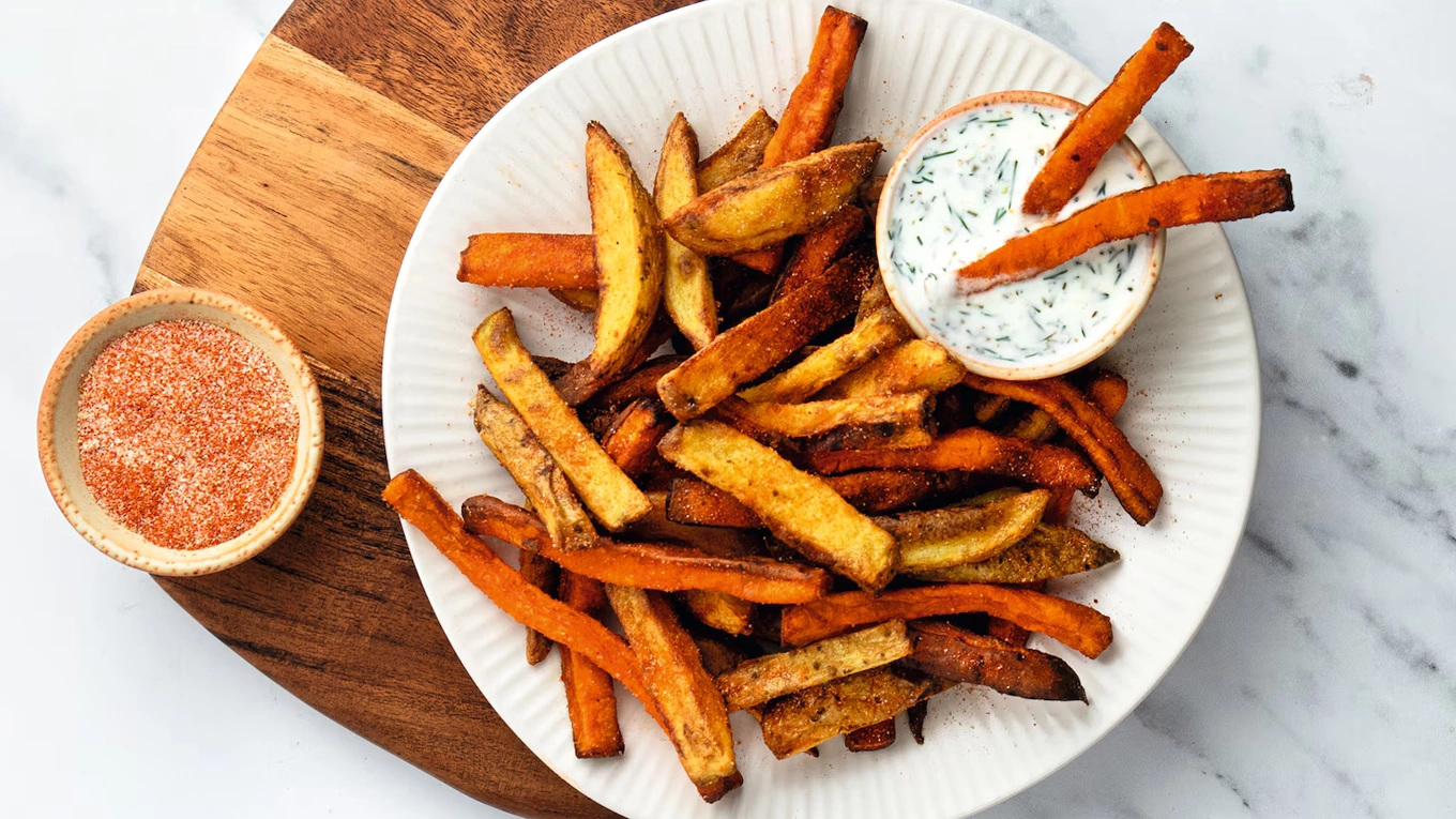 süßkartoffelpommes aus dem airfryer süßkartoffelpommes mit dip auf einem teller auf einem holzbrett
