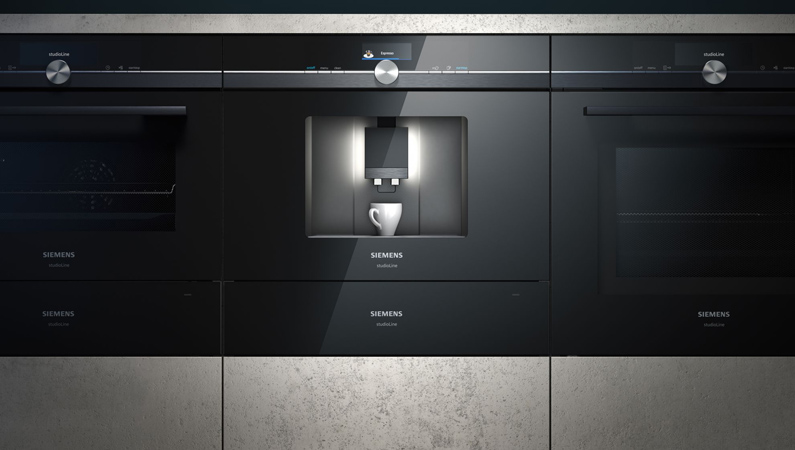 weiße kaffeetasse unter einem siemens studioline kaffeevollautomat zwischen zwei backöfen in einem küchenschrank