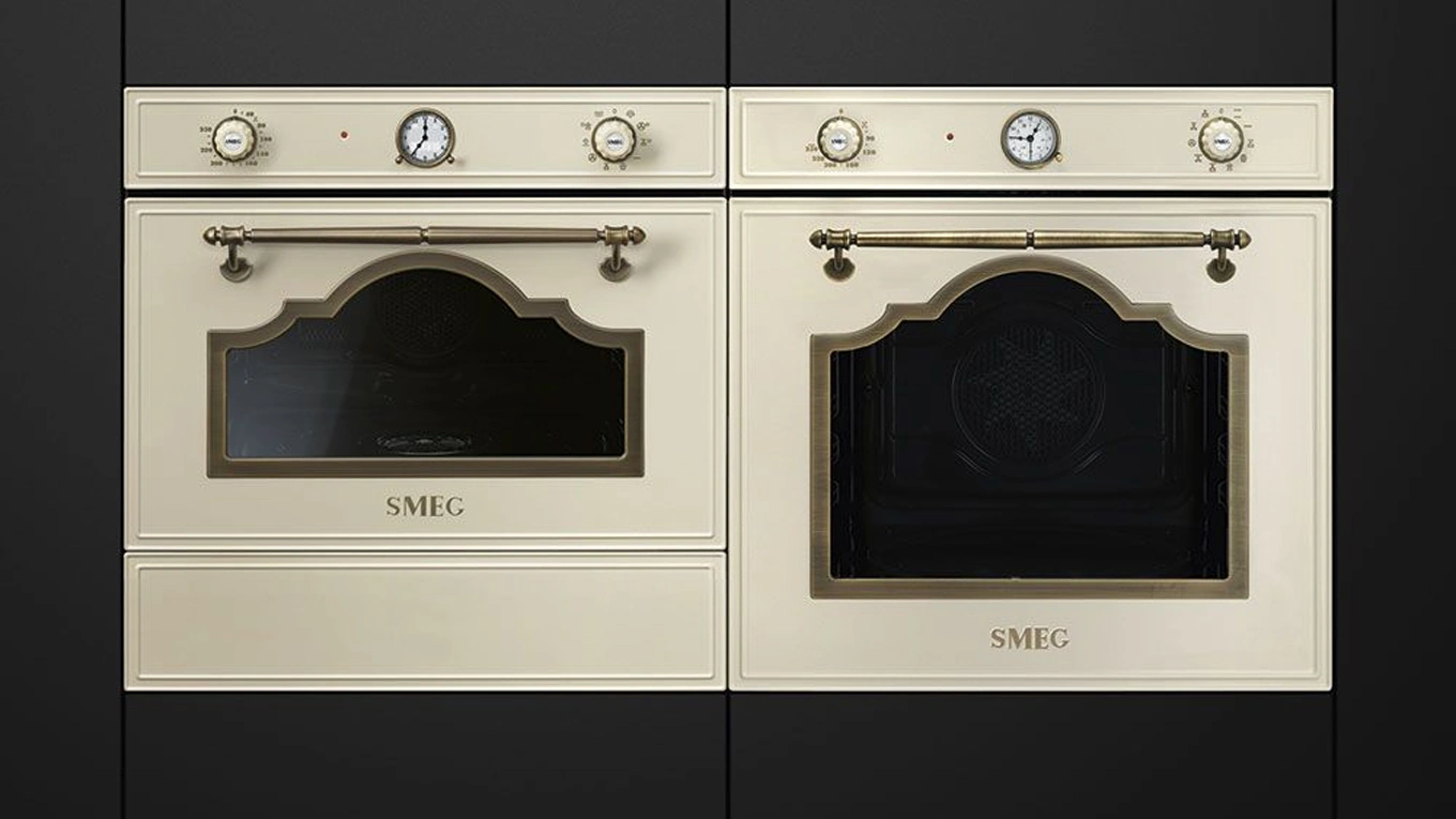 zwei smeg cortina backöfen in creme mit details in gold in einer schwarzen küchenfront