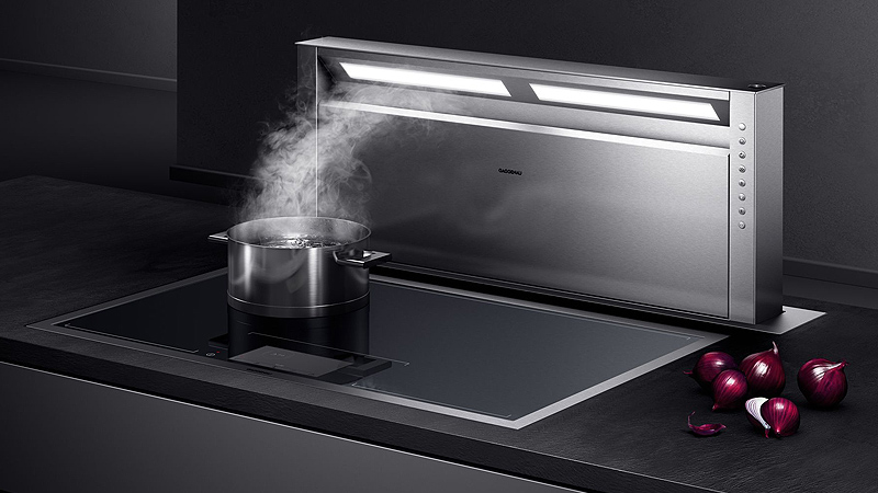 Gaggenau Serie 400 Dunstabzugshauben ein silberner edelstahl tischluefter aus der gaggenau serie 400 mit eingeschaltetem licht saugt im dunkeln wasserdampf aus einem topf am kochfeld ab