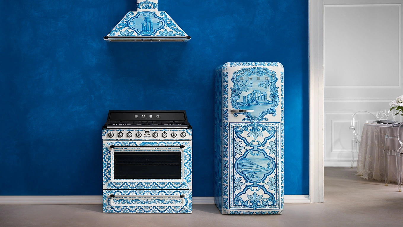 smeg dolce gabbana majolika kollektion mit standherd und kühlschrank in blau weiß vor einer blauen wand