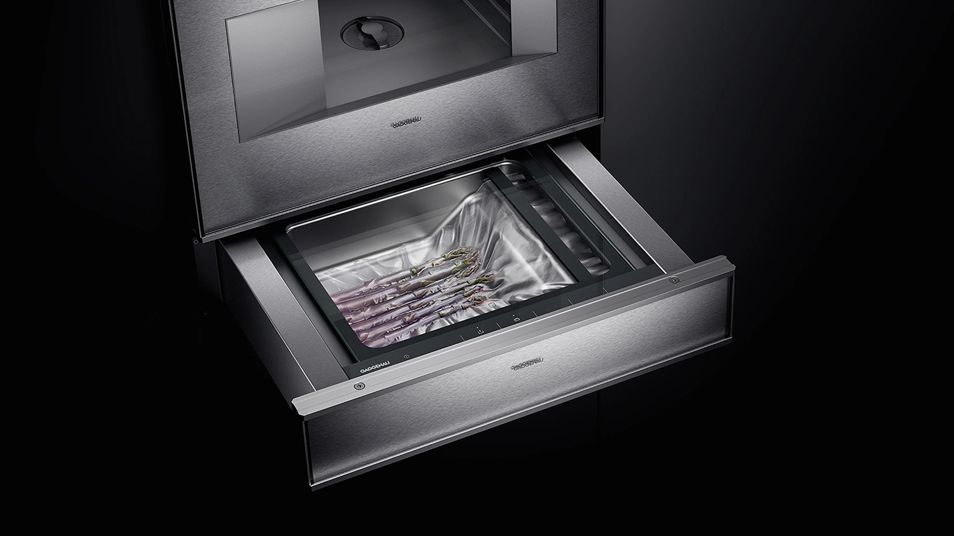 Geöffnete Vakuumierschublade von Gaggenau in Silber unterm Backofen mit Vakuumiertem Lebensmittel