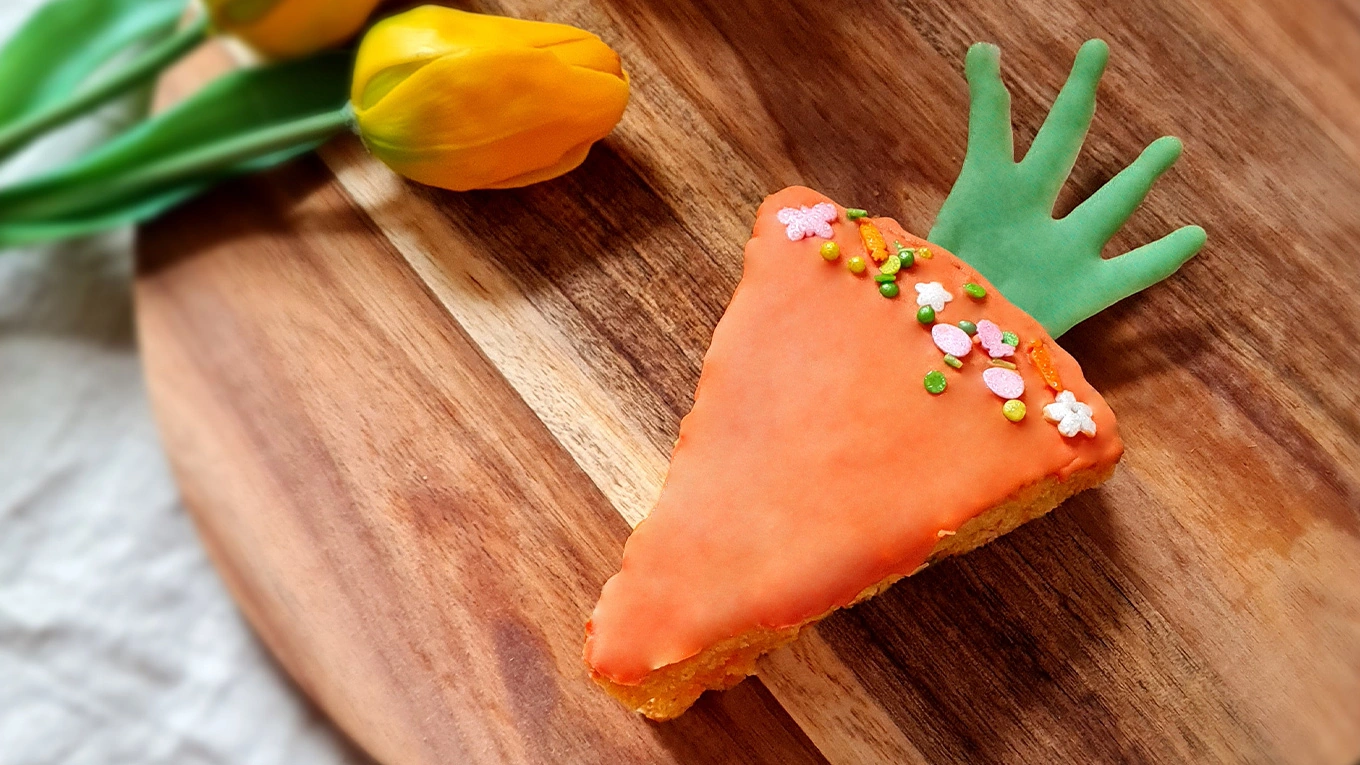 Möhrenkuchen Kuchenstück in Möhrenform auf einem Holzbrettchen