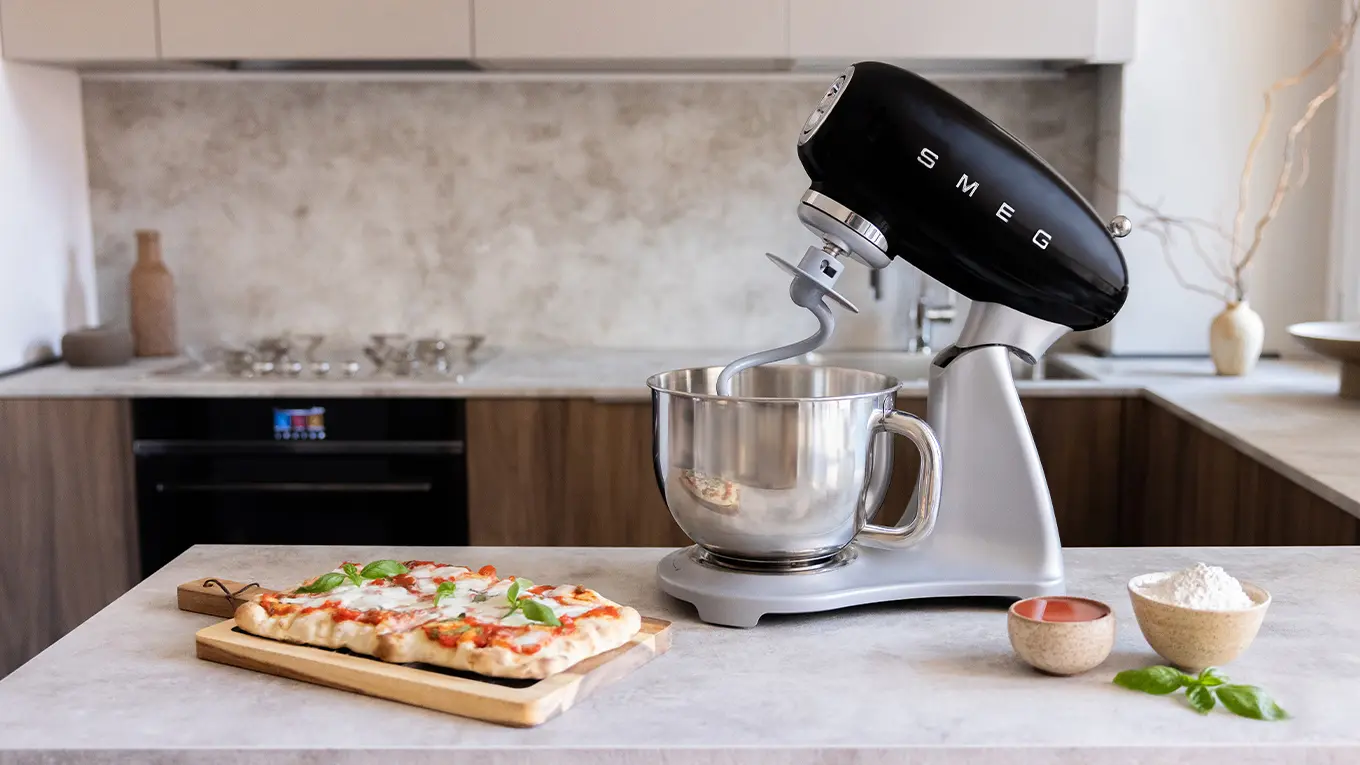 smeg smf04 retro küchenmaschine in schwarz neben pizza auf einem holzbrett