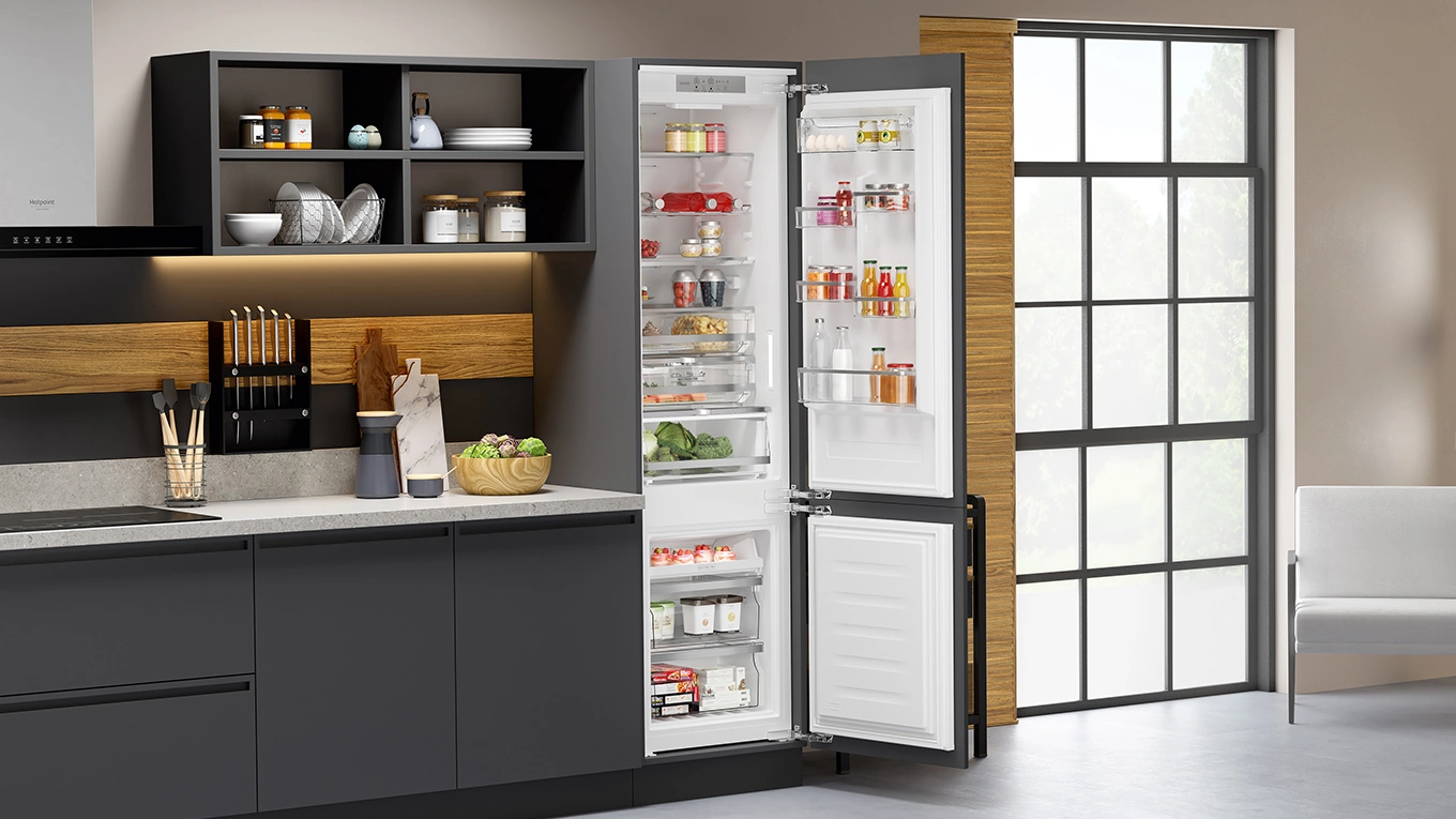 Bauknecht Einbau-Kühl-Gefrierkombination mit untem liegenden Gefrierfach und geöffneter Tür mit Blick auf Lebensmittel in einer Beispielküche