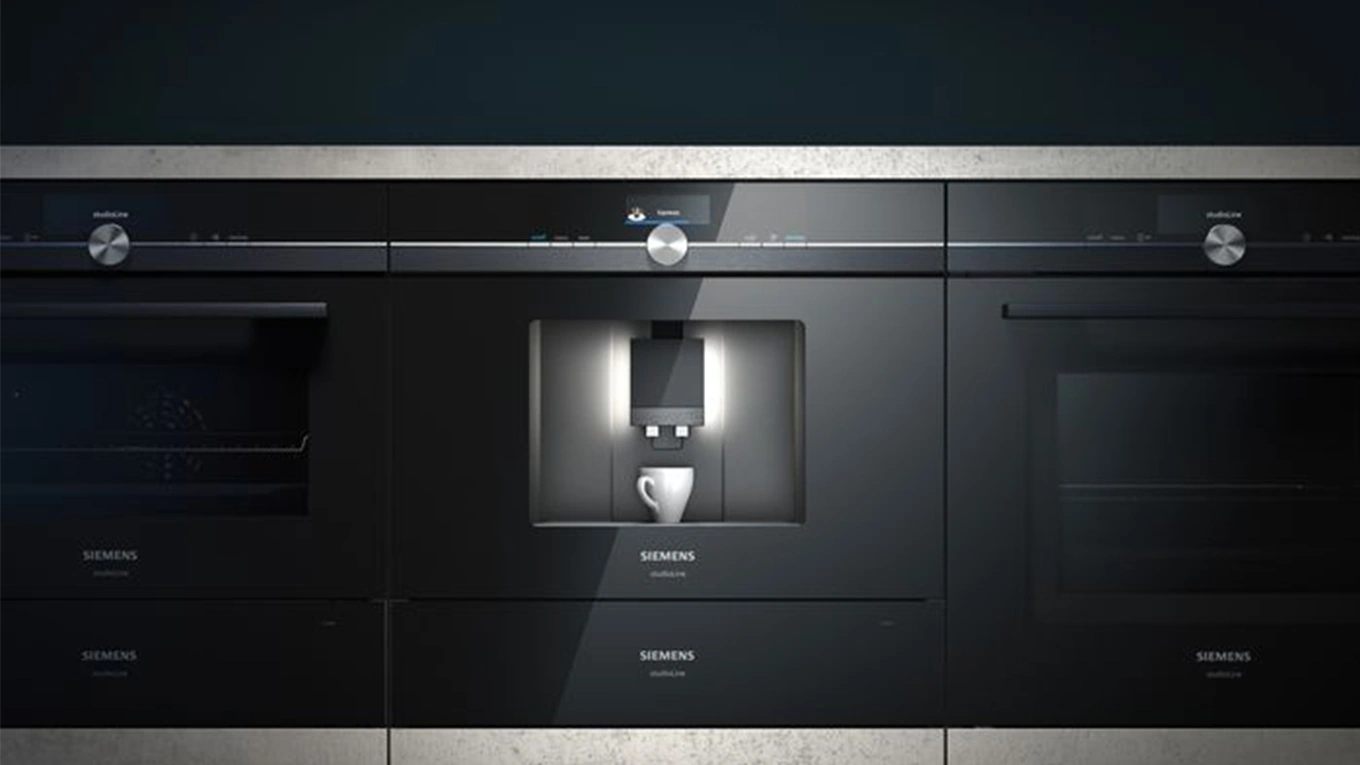 Siemens studioLine Kaffeevollautomat schwarzer siemens studioline kaffeevollautomat mit weißer Tasse neben Backöfen eingebaut