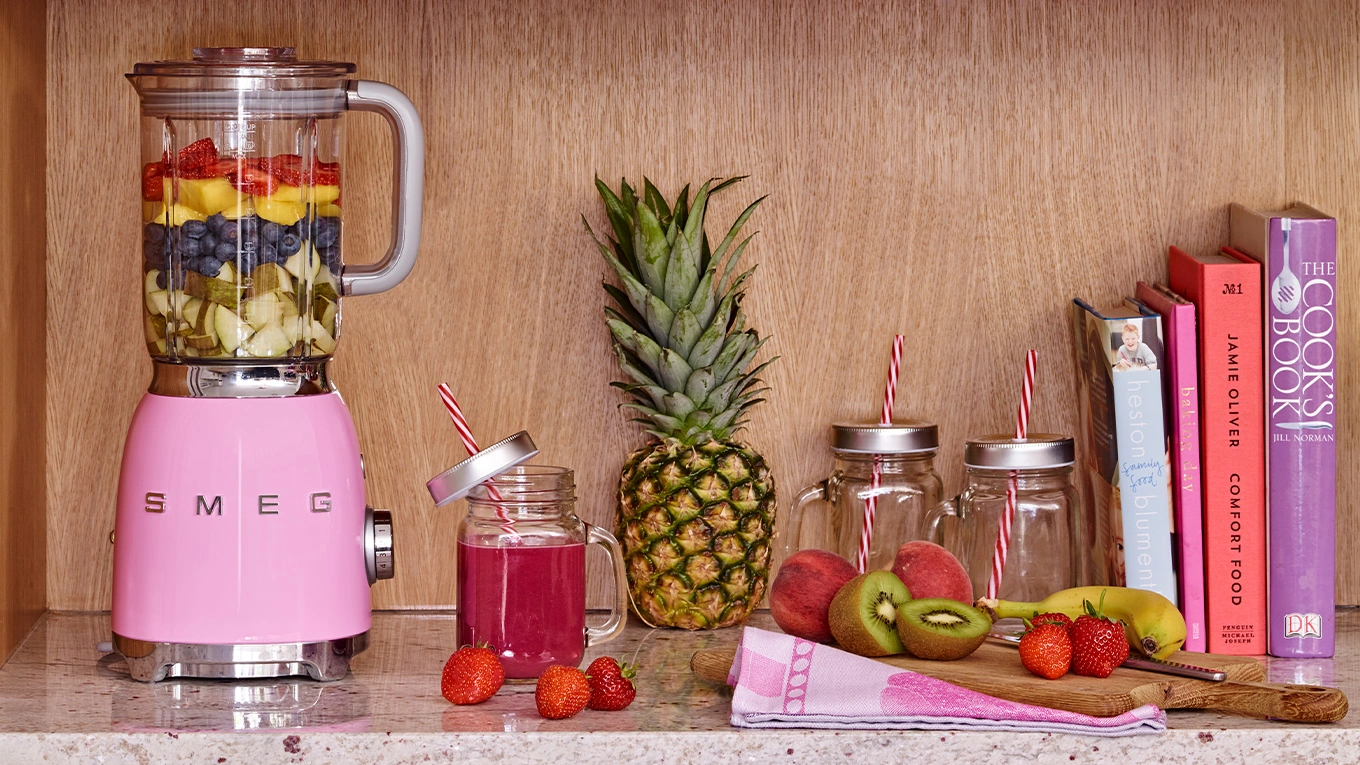smeg mixer in cadillac pink smeg mixer in cadillac pink mixt smoothie und steht im regal neben büchern und früchten