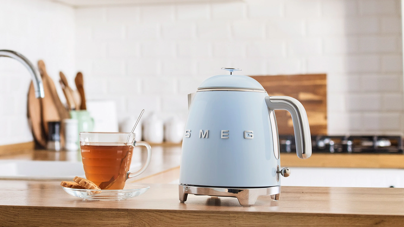 smeg mini wasserkocher in pastellblau neben einem Teeglas auf einer Küchen-Arbeitsplatte