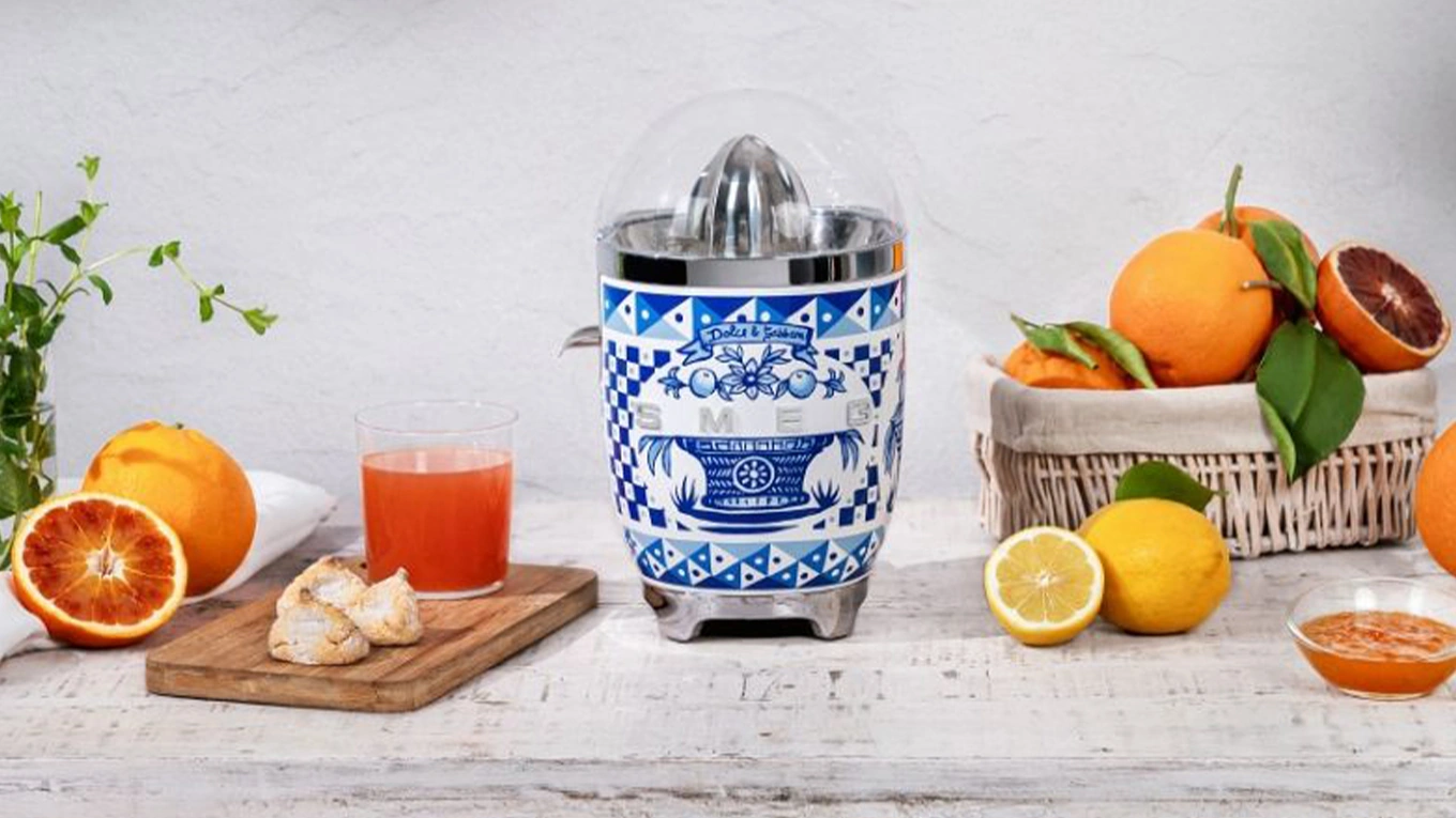 smeg dolce & gabbana blue mediterraneo saftpresse in blau weiß retro sommer stil neben zitrusfrüchten