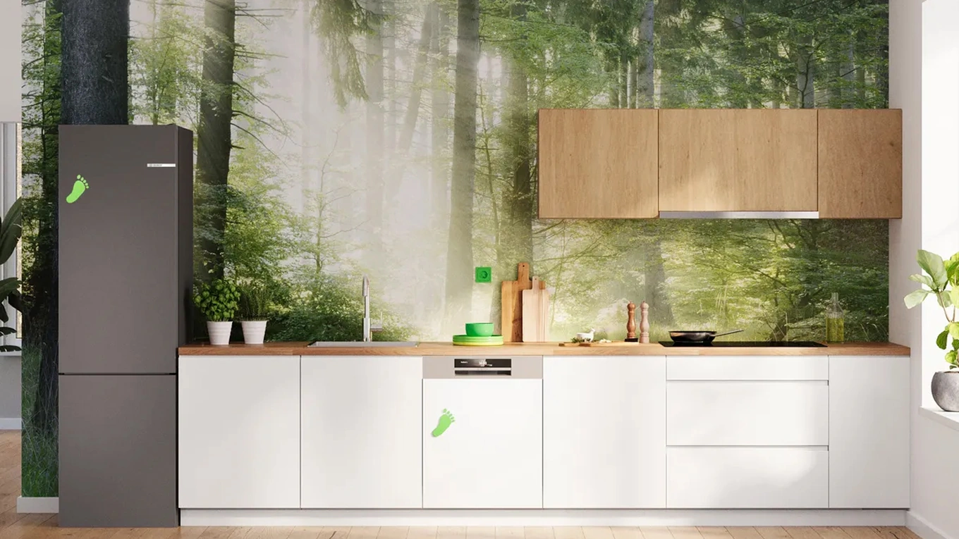 Bosch Green Collection Bosch Green Collection Kühlschrank und weitere Küchengeräte in einer weißen Küche vor einer Wald Tapete