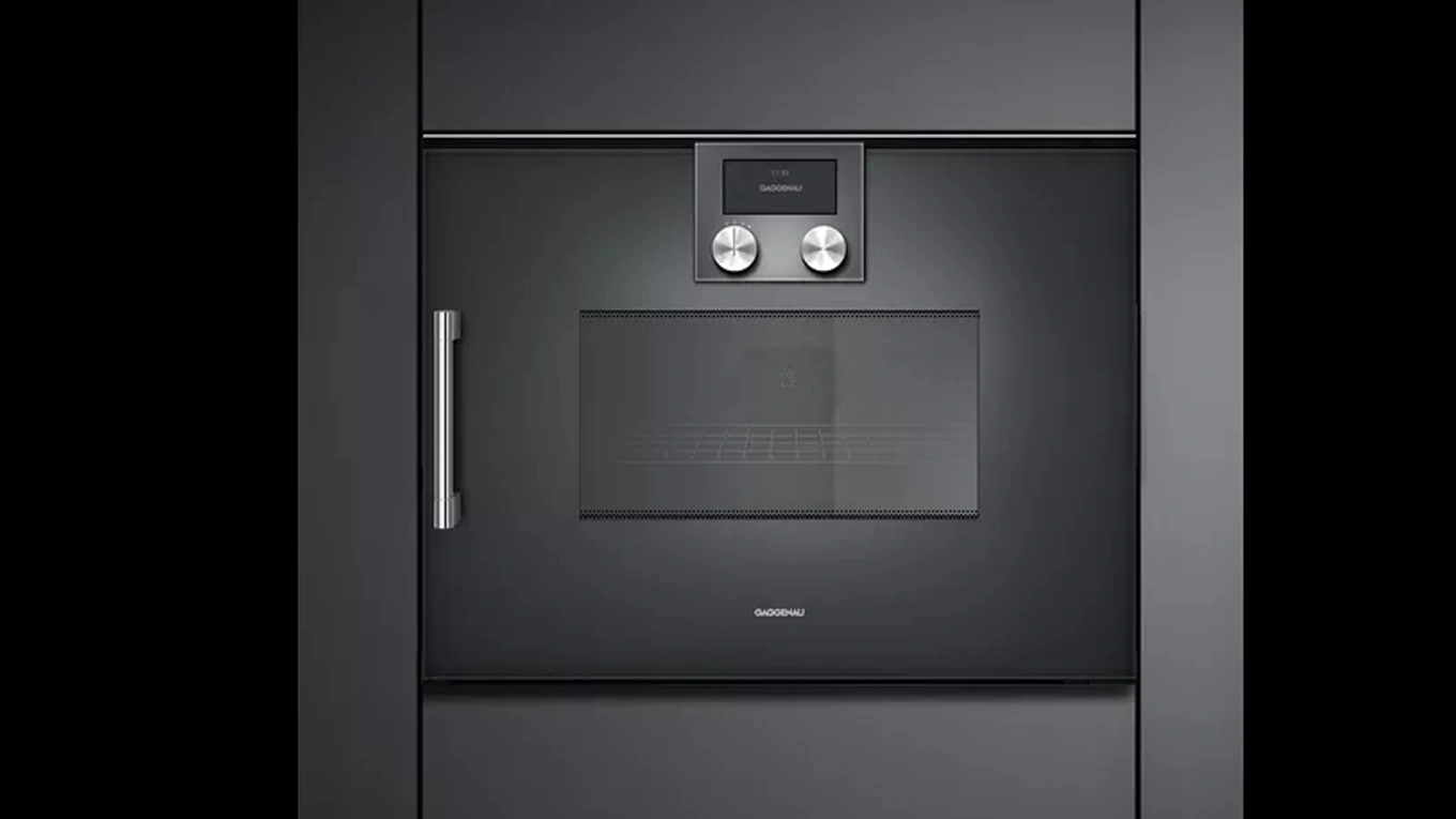 Schwarzer Mikrowellen-Backofen aus der Gaggenau Serie 200 mit Griff in einer dunklen Küchenfront eingebaut
