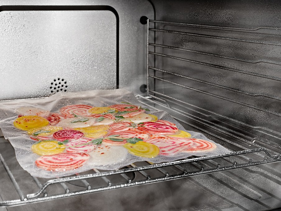 Vakuumierte Gemüsescheiben beim Sous Vide Garen auf einem Rost im Miele Dampfbackofen