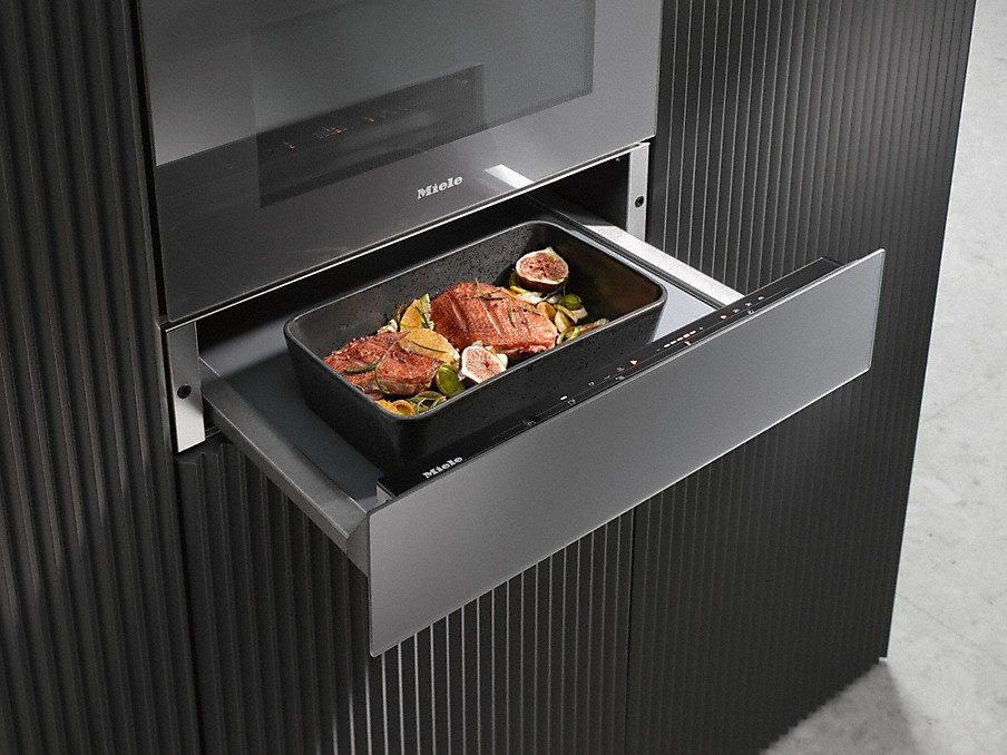 Miele Niedrigtemperaturgaren schwarzer bräter mit fleischstücken in einer miele wärmeschublade für niedrigtemperaturgaren