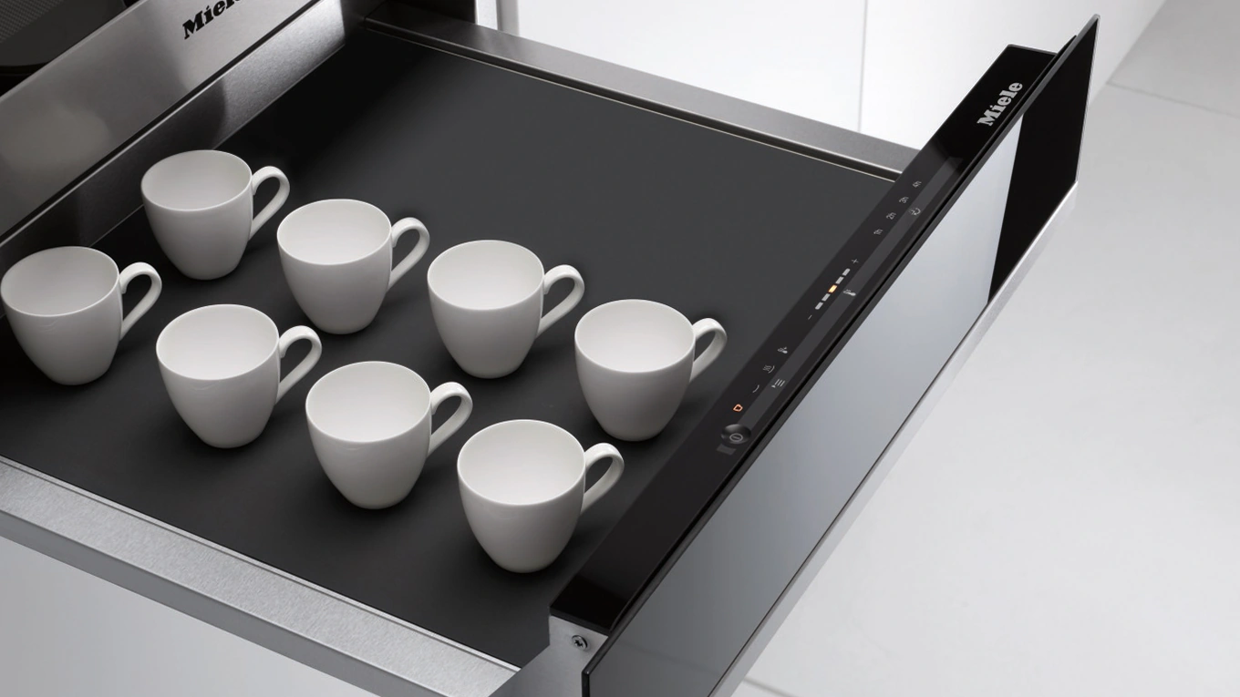 Miele Wärmeschublade mit Antirutschmatte Weiße Espressotassen auf einer schwarzen Antirutschauflage in einer miele Wärmeschublade