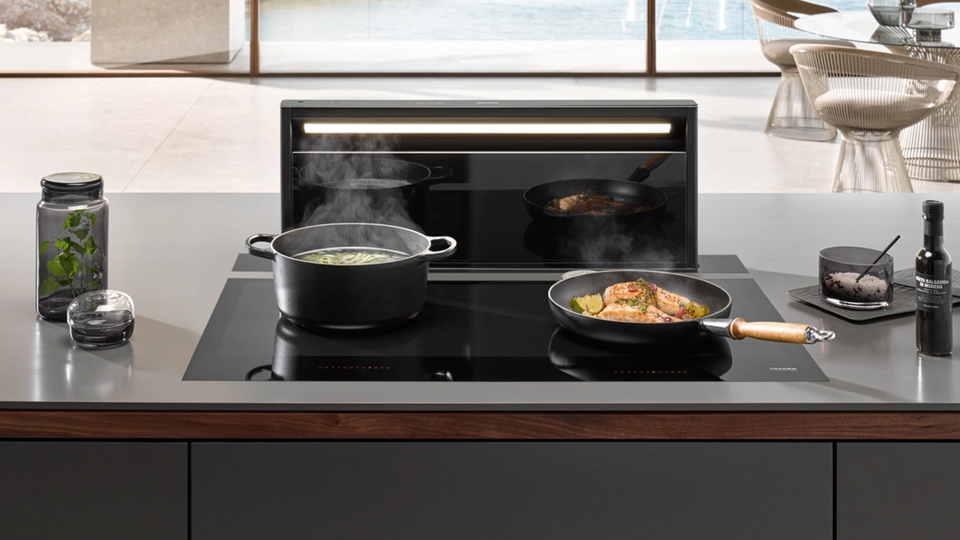 Miele Black Levantar Tischlüfter Kochfeld mit Miele Black Levantar Tischlüfter beim Absaugen von Dampf aus einem Topf und einer Pfanne