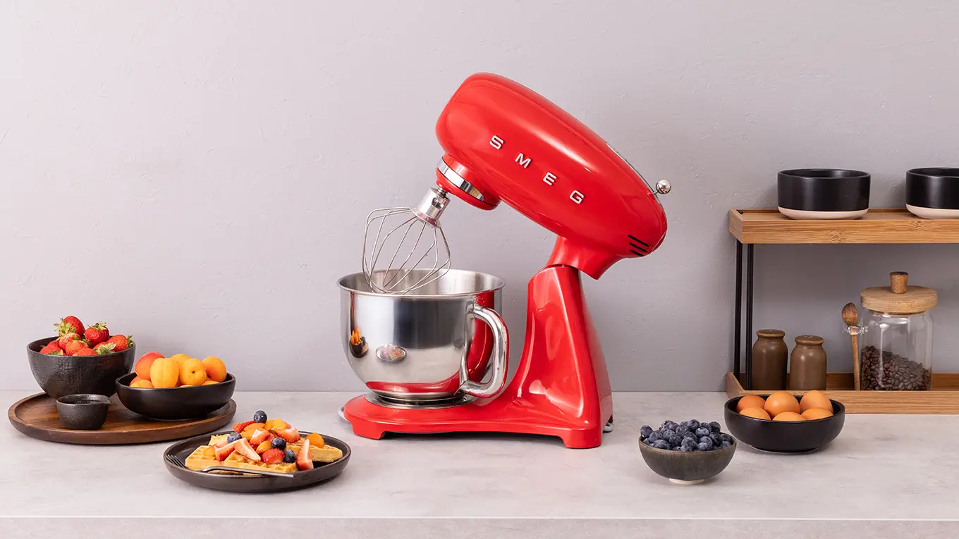 rote smeg küchenmaschine smf05 mit schüsseln und teller voll früchten