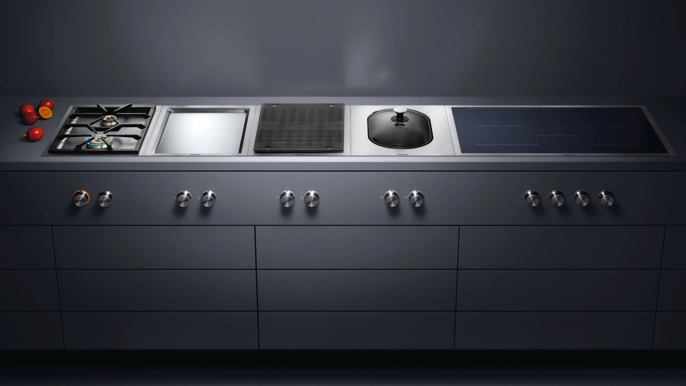 gaggenau vario kochfelder mit gas und induktion Breites Vario Kochfeld von Gaggenau mit nebeneinander liegenden Gaskochfeld Teppanyaki, Grill, Wok und breitem Induktionskochfeld in einer dunklen kochinsel eingebaut