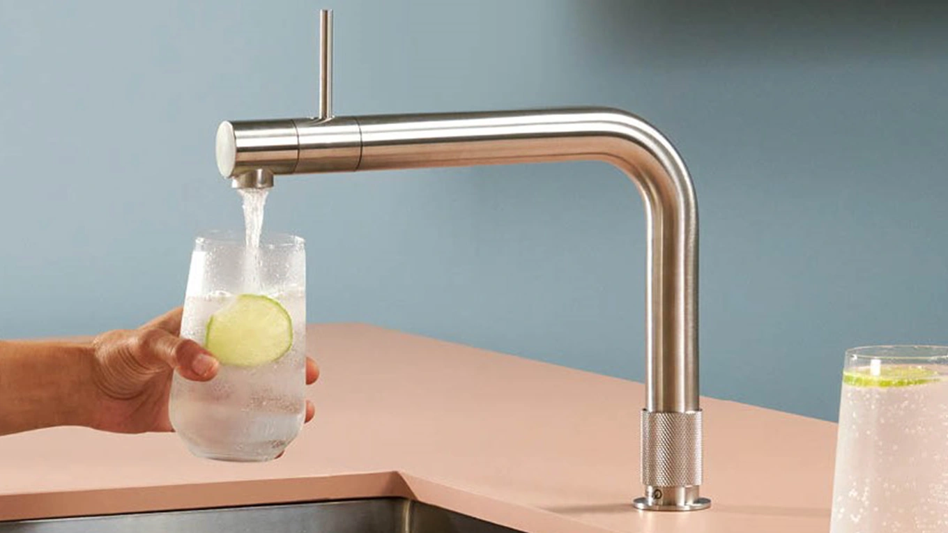 quooker front in edelstahl quooker front wasserhahn in edelstahl befüllt ein glas mit limettenscheibe mit kaltem sprudelwasser