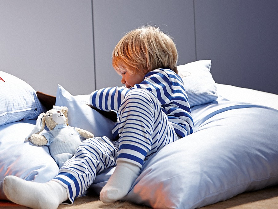 Miele Silence System kleinkind im blau-weiß gestreiftem schlafanzug mit kuscheltier auf kissen