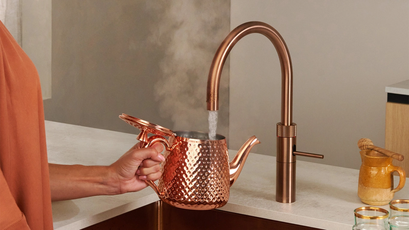 Quooker Kupfer Rosé frau füllt kochend heißes wasser aus dem quooker kupfer rose in eine teekanne