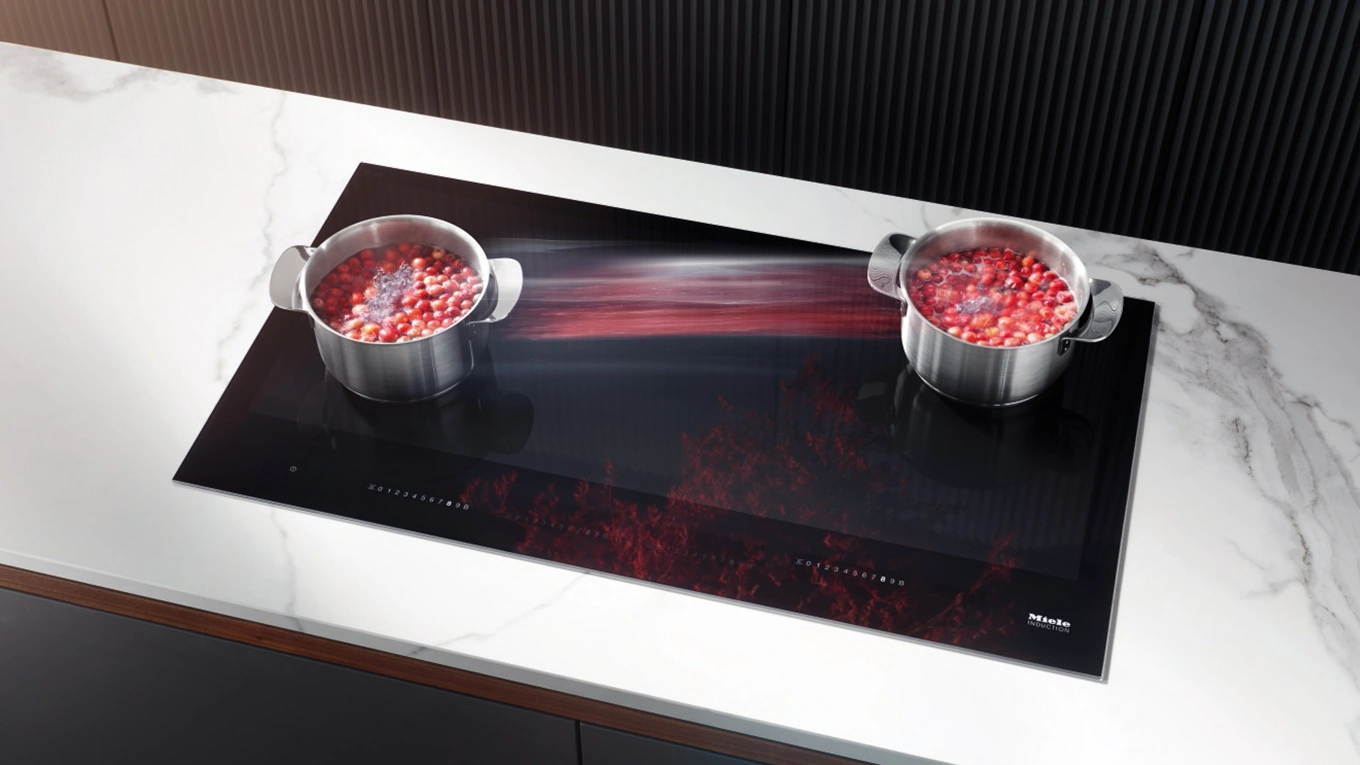 miele induktionskochfeld mit topferkennung zwei diagonal platzierte töpfe mit rotem inhalt und rot verwaschener verbindungslinie auf einem miele induktionskochfeld mit topferkennung